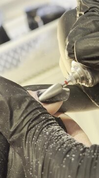 Professional nail technician giving a manicure to a client, showing hands and nail details in close-up. Modern salon setting, precise and clean work