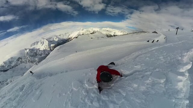 A snowboarder skis down a mountainside and falls. Freeride, powder, white slopes, winter atmosphere. Distorted perspective. Real people. MegaView. UltraWid. ActionView