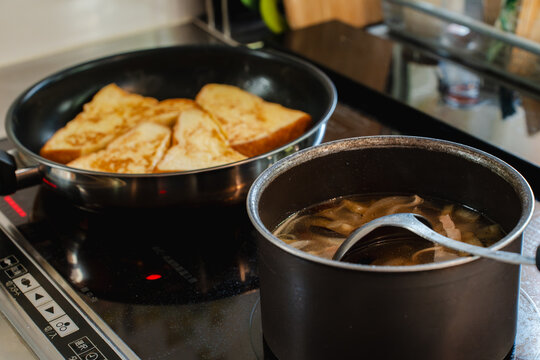 コンロでフレンチトーストを焼きスープを温める朝食準備
