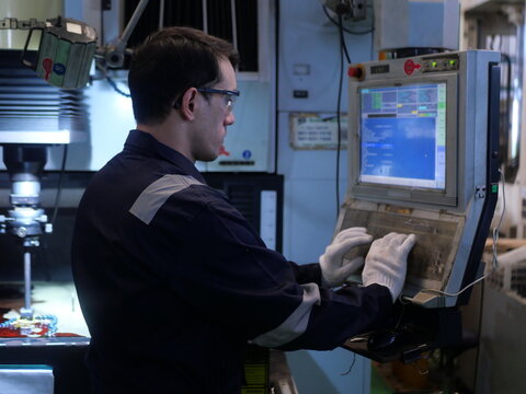 Factory engineer inspecting machining process on CNC machine in automotive manufacturing plant