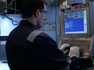 Fototapeta premium Factory engineer inspecting machining process on CNC machine in automotive manufacturing plant