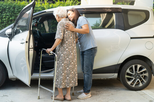 Caregiver help Asian elderly woman disability patient get into car.