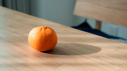 木目のテーブルに置かれたみかん 自然光が差し込む部屋 ミニマルな静物 / Fresh oranges on wooden table with dramatic natural light and shadows, minimalist still life