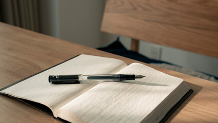 ノートに書き物をする男性の手元 思考の整理 ジャーナリング 丁寧な暮らし / Hands writing in notebook with pen and orange on table, journaling and planning concept