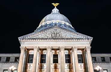 Obraz premium Mississippi State Capitol building in Jackson. Historic Beaux-Arts government architecture features illuminated Corinthian columns and a dome topped with a gold eagle statue at night