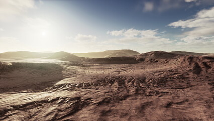 Endless expanse of dry desert stretches under a bright sky as the sun casts shadows across rolling hills. Clouds drift slowly in the distance, creating a serene atmosphere. © icetray