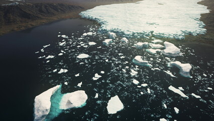 Majestic icebergs drift gently in a tranquil Arctic fjord. The dark waters reflect the vibrant colors of the sunset while the icy landscape showcases natures stunning beauty and fragility. © icetray
