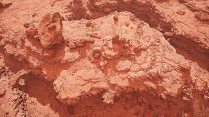 Fototapeta premium Unique rock formations create an otherworldly scene in a red hued environment. The terrain appears rugged and unearthly, showcasing natural geological patterns and textures.