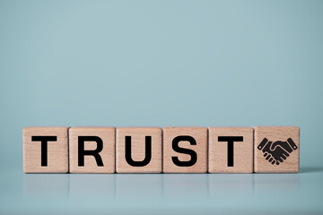 Trust business concept with trust on wooden blocks and handshake icon. Corporate integrity, partnership reliability, brand credibility, customer confidence and long term business relationship theme.