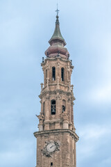 Obraz premium Detailed view of the Baroque bell tower of La Seo Cathedral in Zaragoza, Spain. This architectural close-up highlights the intricate brickwork, sculptures, and clock of the historic landmark