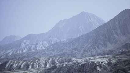 Obraz premium Soft mist envelops a stunning mountain range at dawn, highlighting the rocky textures and contours. Natures peaceful beauty is captured in this serene landscape, evoking a sense of tranquility.