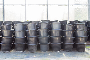 Black plastic plant pot stack by green house, agriculture industry concept