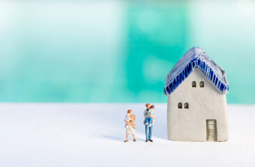 Miniature family people with house model over blurred background, family house, property and real estate business concept