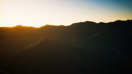 As the sun sets behind the mountains, dark silhouettes emerge against the vibrant sky, creating a tranquil atmosphere perfect for reflection and peace.