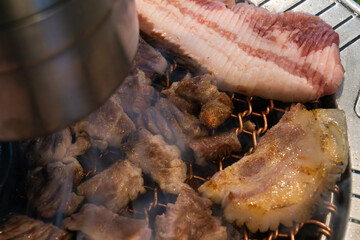 roasting pork belly on charcoal grill in a Korean restaurant
