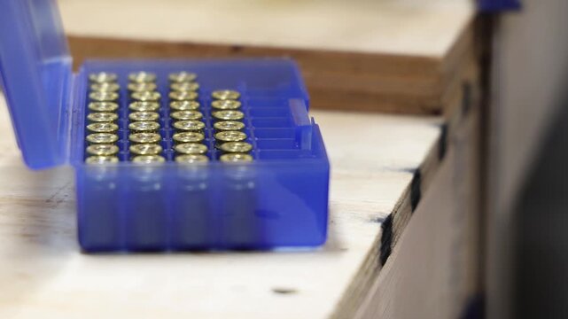 A blue plastic case filled with brass cartridges arranged in neat rows on a wooden surface
