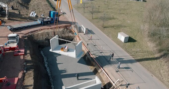 Mobile crane lifting precast concrete walls at construction site