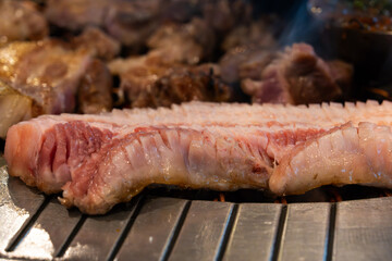 roasting pork belly on charcoal grill in a Korean restaurant