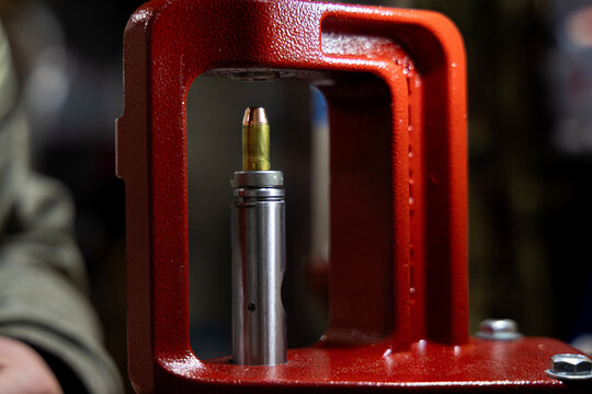 Close-up of a bullet casing being loaded into a reloading press for ammunition manufacturing