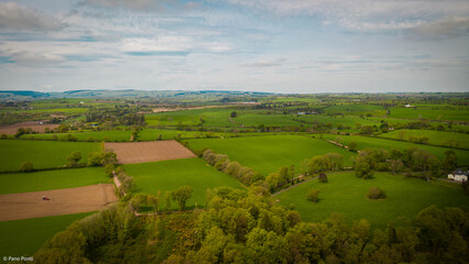 Obraz premium Aerial View of Green Farmland and Fields Under Cloudy Sky, Ireland