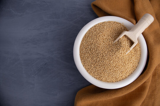Bowl of Amaranth Grains with Wooden Scoop on Dark Background