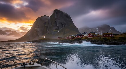 Coastal village with red houses sits by a rough sea and dramatic mountain.