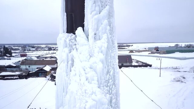 A frozen water tower. The water has turned to ice. It's abnormally cold. An ice-covered iron structure that holds water. An ice-covered iron water tower.