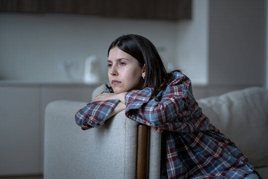 Bored frustrated teen girl feeling no motivation, lack of dopamine sitting alone on couch sadly looking. Lost in thoughts girl rest on sofa put head on armrest at home have low energy, apathy, stress