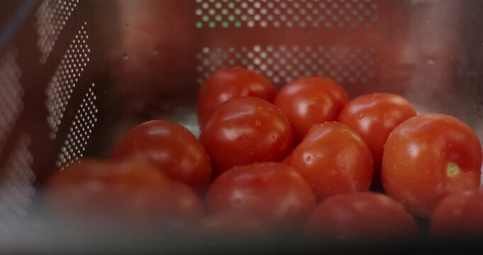 Fresh red tomatoes with water drops in stainless steel colander