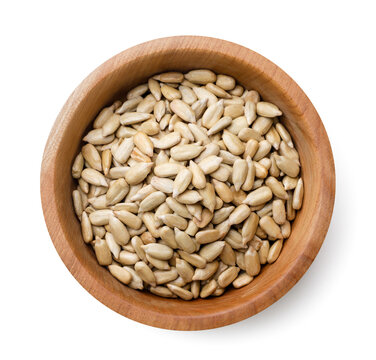 Peeled sunflower seeds, sunflower kernel in a wooden plate on a white background. Top view