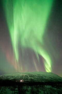 Northern lights swirling in the sky above Nuolja mountain in Sweden near STF Abisko