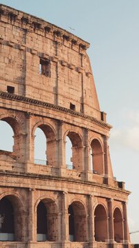 Famous Roman Colosseum, an ancient amphitheater and UNESCO world heritage site, glowing under the warm sunlight of a clear day, a testament to imperial Roman architecture and history in Italy