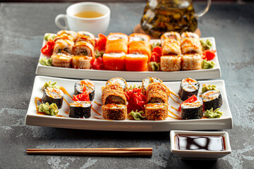 Japanese sushi rolls assortment with salmon crab sesame nori and wasabi served on white plates with soy sauce © Hihitetlin