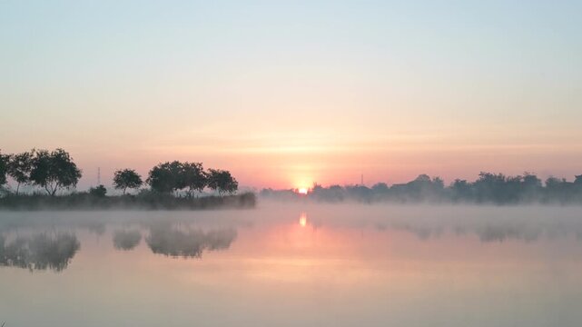 Morning time on the lake and mist fog.The trees and foggy with sun rise sky and reflective in the water.Natural landscape in the morning time.
