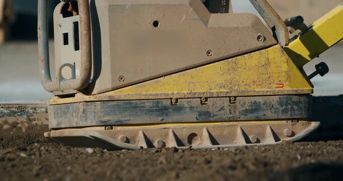 Yellow vibrating plate compactor on construction site ground