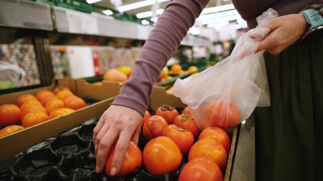 Woman Choosing Fresh Persimmon While Shopping At The Fruit Section In The Supermarket