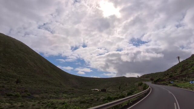 Bergstra&szlig;e auf Lanzarote durch eine gr&uuml;n bewachsene felsige vulkanische Landschaft bew&ouml;lktem Himmel am Horizont, reisen, Roadtrip, Kanarische Inseln, Spanien, bergauf, Urlaub