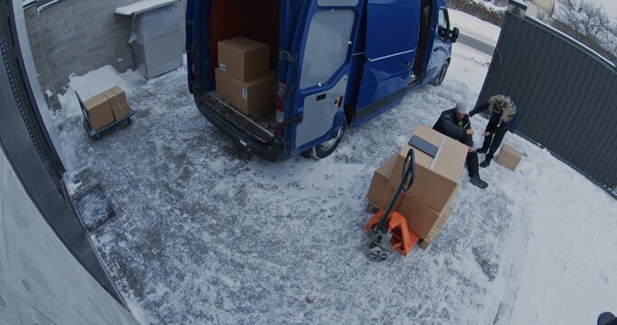 Adult Man Slips and Falls on Ice While Carrying Box From Van. Woman Runs From Warehouse to Help Injured Colleague. CCTV Footage Highlights Winter Workplace Hazards and Slip Trip Fall Accidents.