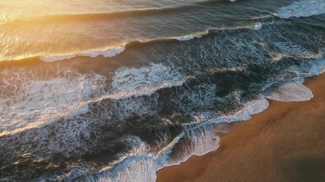 Spectacular aerial drone shot of waves in Nazar&eacute; during sunset. Raw Portuguese cliffs and golden water without a trace of civilization. This cinematic footage captures the powerful Atlantic Ocean 