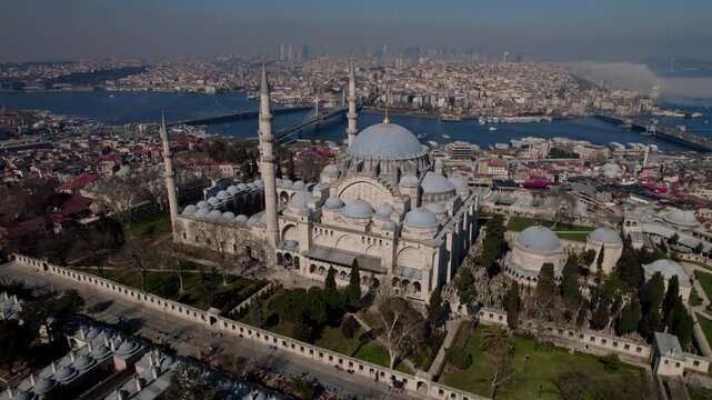 Aerial drone footage of S&uuml;leymaniye Mosque in Istanbul, featuring Ottoman architecture with domes and minarets, the Golden Horn, Halic Bridge, boats and the historic city skyline.