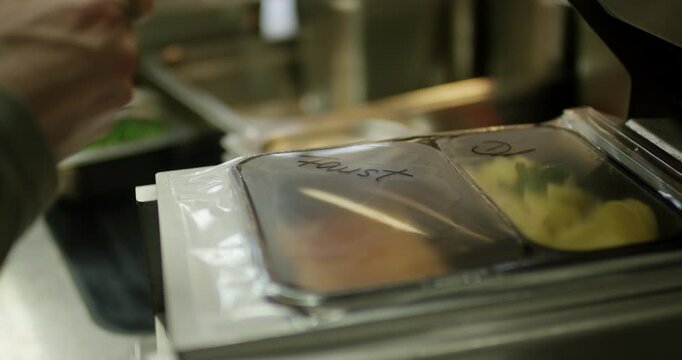 Staff member hand labeling prepackaged catering meals for organization and delivery