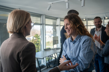 Obraz premium Two professional women talking and smiling during break in cozy office environment