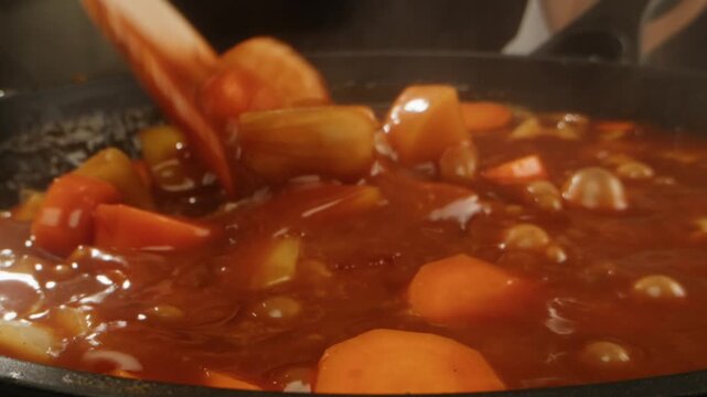 Hungarian goulash soup cooking close-up in pot, chef cook traditional polish or zech soup in restaurant. 