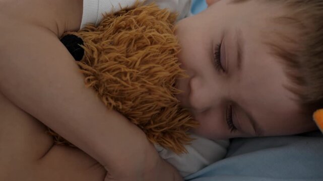 A small child is sleeping peacefully, hugging a soft plush toy. Close-up of a child's face with closed eyes, an atmosphere of comfort, safety and tranquility. The concept of childhood