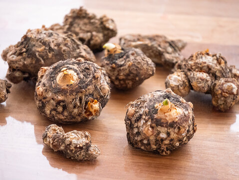 Several brown konjac plants with green sprouts on a wooden background, healthy food for diet and culinary purpose
