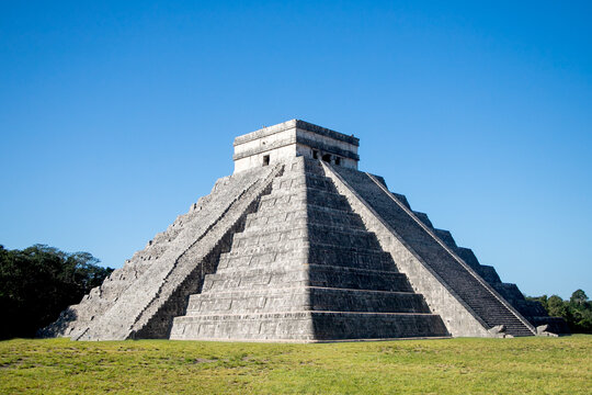 The iconic El Castillo pyramid, also known as the Temple of Kukulcan, stands majestically against a vibrant blue sky, showcasing its ancient Mayan architecture at Chichen Itza