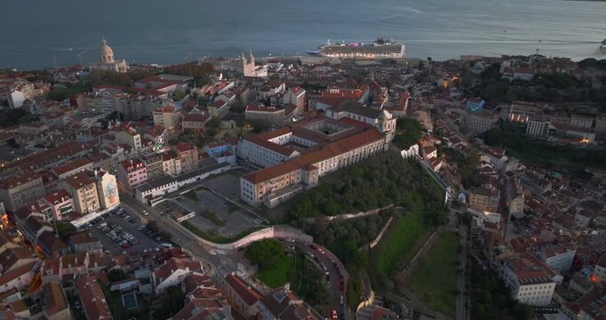 Drone shot revealing Lisbon, Alfama and Graca historic center and surrounding hills with layered architecture and distant river in wide cinematic composition