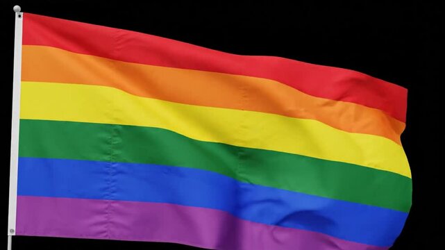 Rainbow flag waving in the wind at a community event during Pride Month celebrations in June
