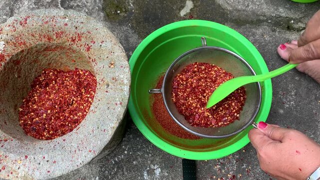 sifting dried hot peppers with strainer traditionally.