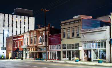 Historic storefronts on North State Street in Jackson, Mississippi. A row of vintage commercial buildings with colorful brick facades and decorative cornices is illuminated by streetlights at night © Leonid Andronov
